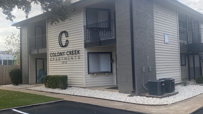 the apartment complex has a parking lot and a sign that says c at The Colony Creek Apartments