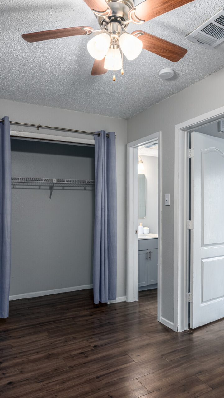 a room with a ceiling fan and hardwood floors at The Colony Creek Apartments