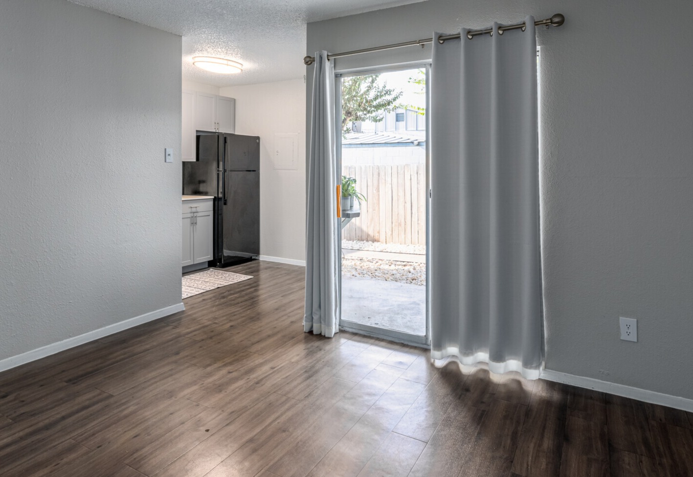 an empty room with sliding glass doors and a sliding glass door at The Colony Creek Apartments