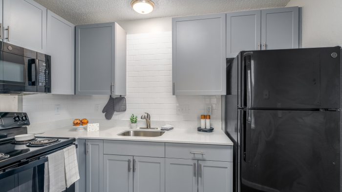 a kitchen with black appliances and gray cabinets at The Colony Creek Apartments