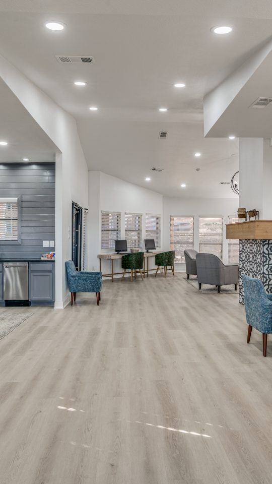 the lobby of a modern apartment building with blue chairs at The Falltree Apartments