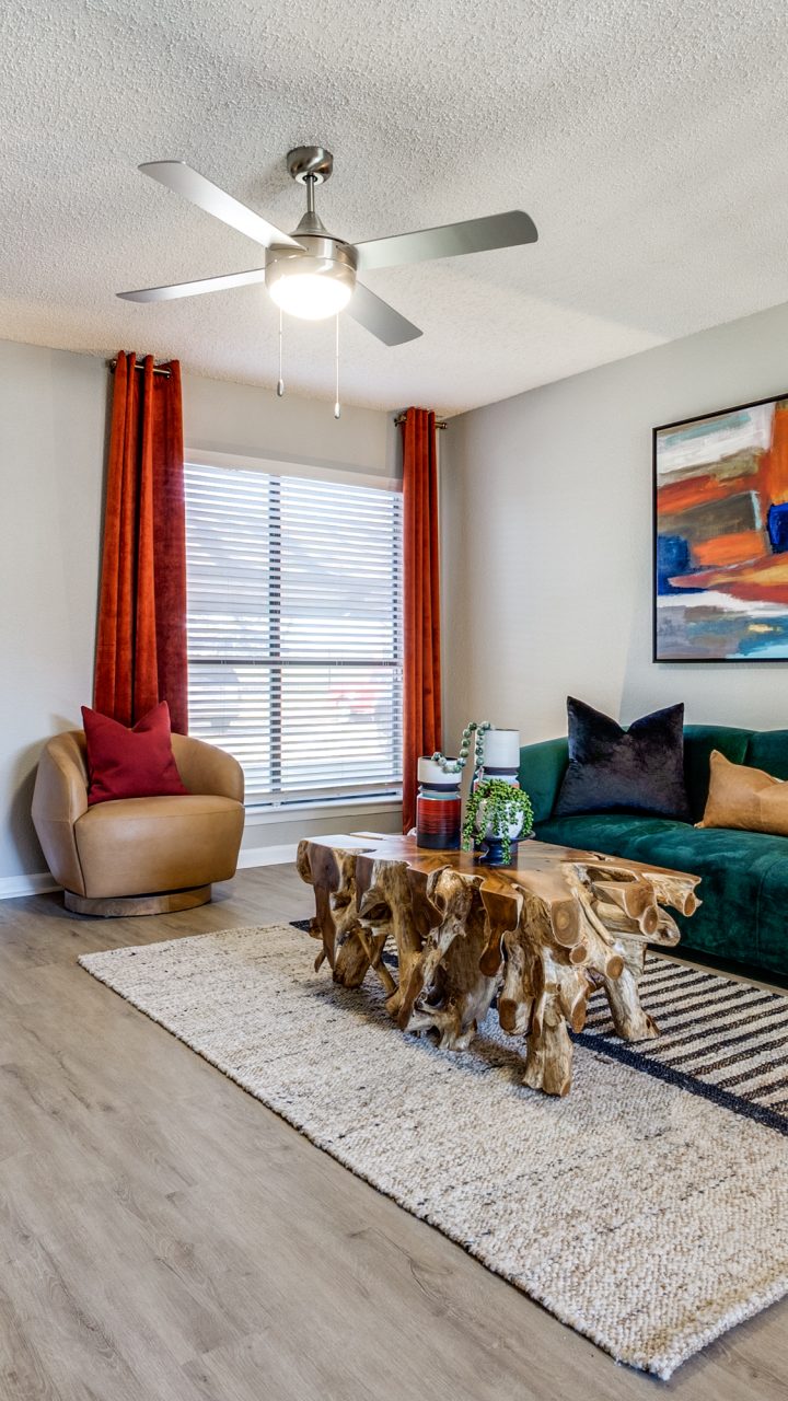 a living room with a green couch and a fan at The Reid Apartments