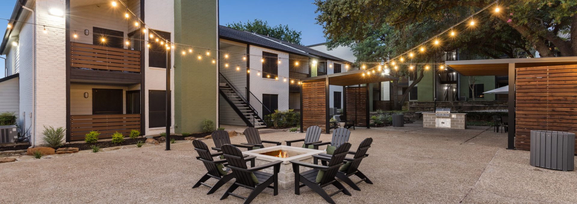 outdoor patio with fire pit and string lights at The  Reid Apartments