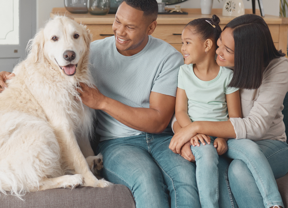 a family sitting on a couch with a dog at The Meadows on Merrill