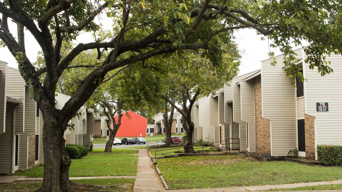 a walkway with trees and a red building in the background at The Meadows on Merrill