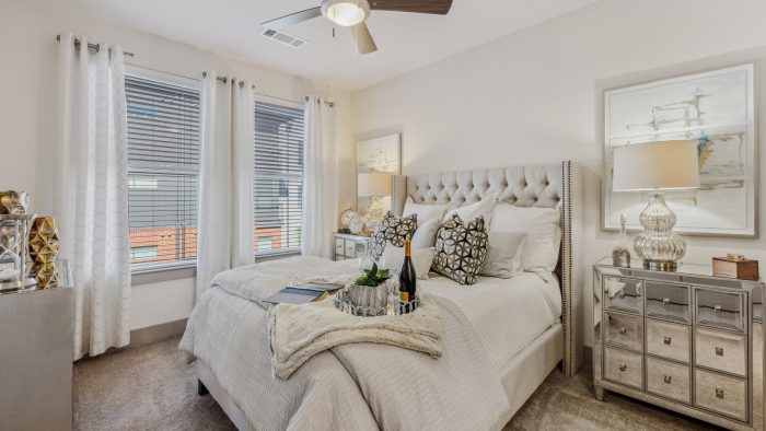 a bedroom with a bed, dresser and ceiling fan at The Steelyard Apartments