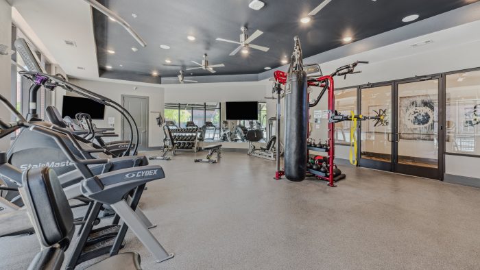 a gym room with exercise equipment and ceiling fans at The Steelyard Apartments