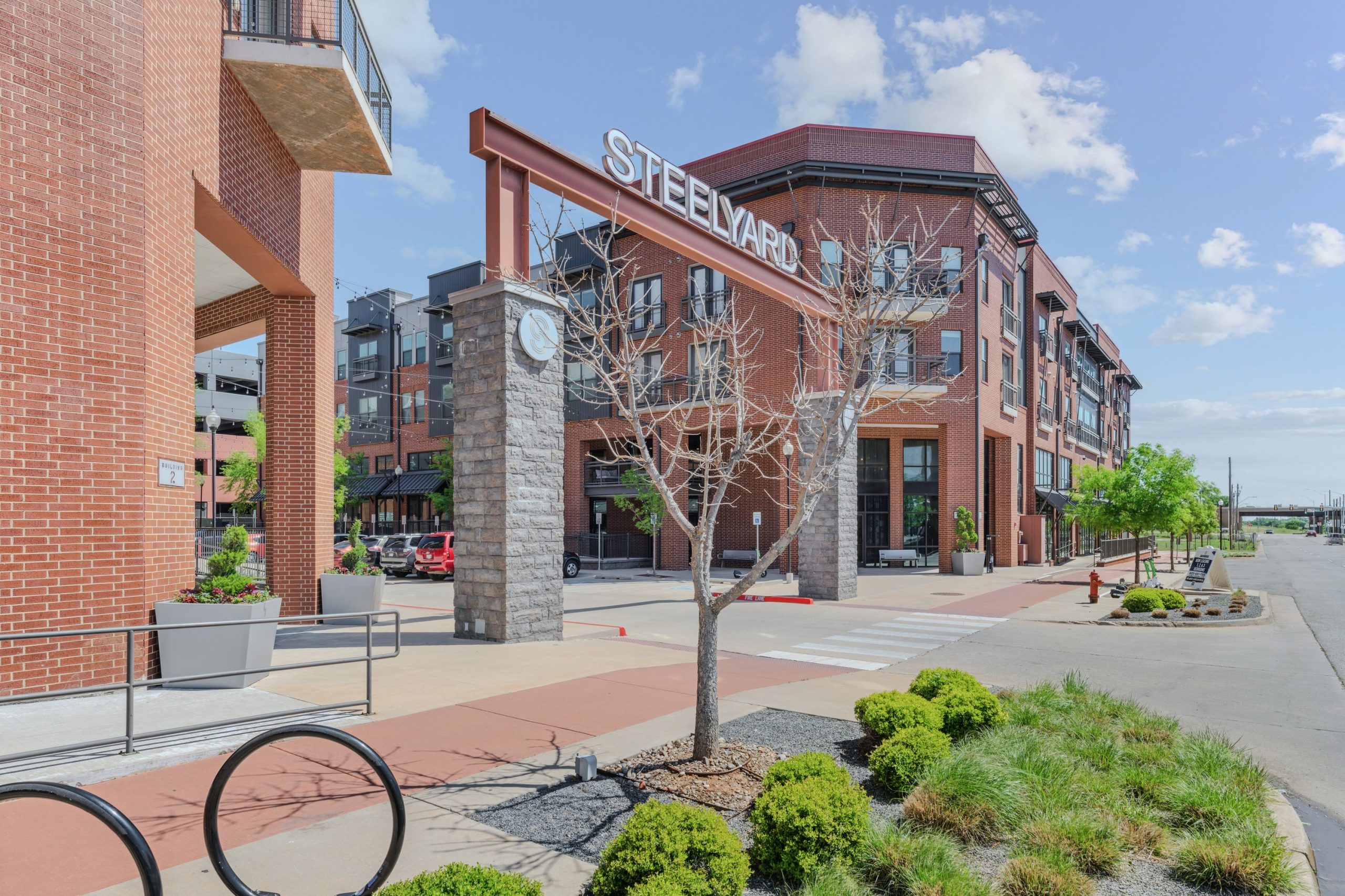 the front of a building with a bike rack and a sidewalk at The Steelyard Apartments