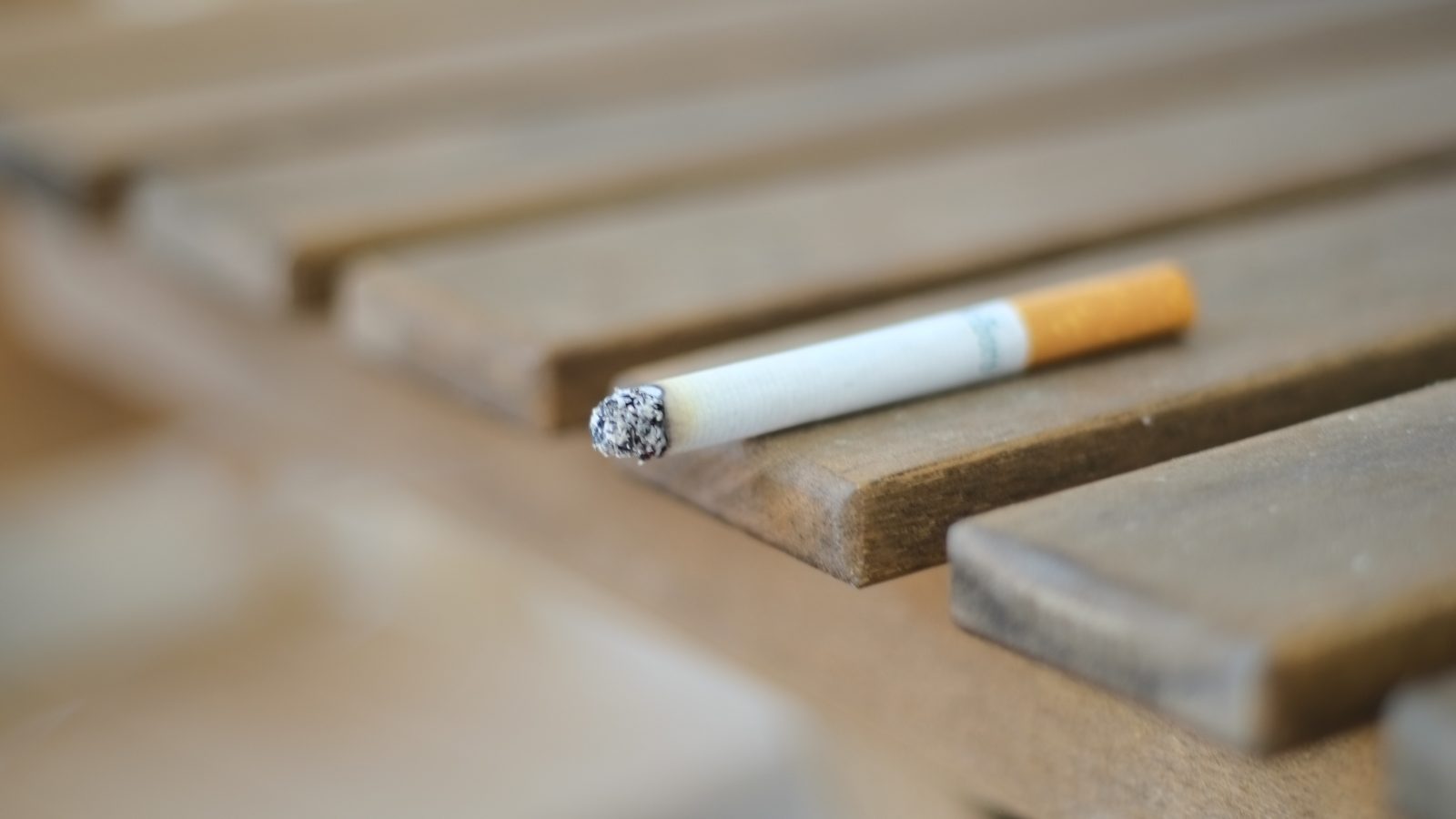 a cigarette sitting on top of a wooden bench