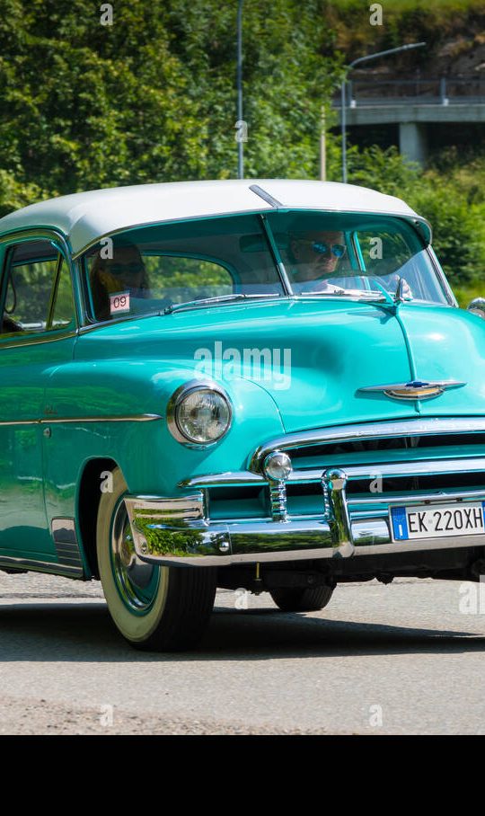 an old blue car is parked on the side of the road
