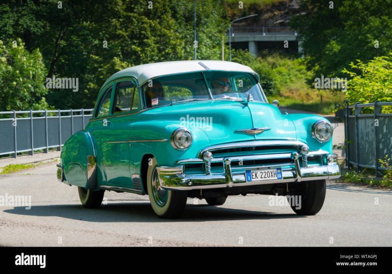an old blue car is parked on the side of the road