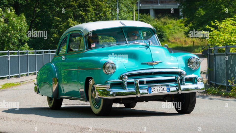 an old blue car is parked on the side of the road