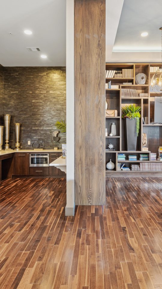 A full size kitchen, tv, bookshelves, and a table with blue chairs