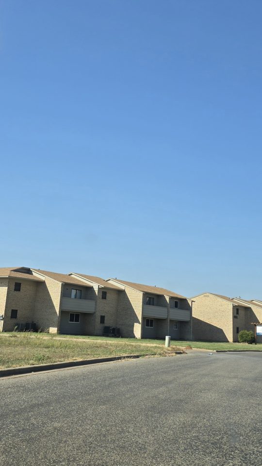 apartment complex with cars parked on the street at The  Courtyard