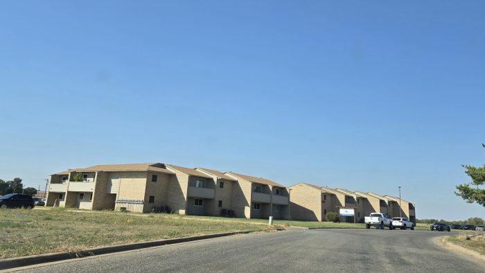 apartment complex with cars parked on the street at The  Courtyard
