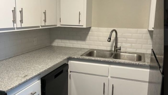 a kitchen with white cabinets and black appliances at The  Courtyard