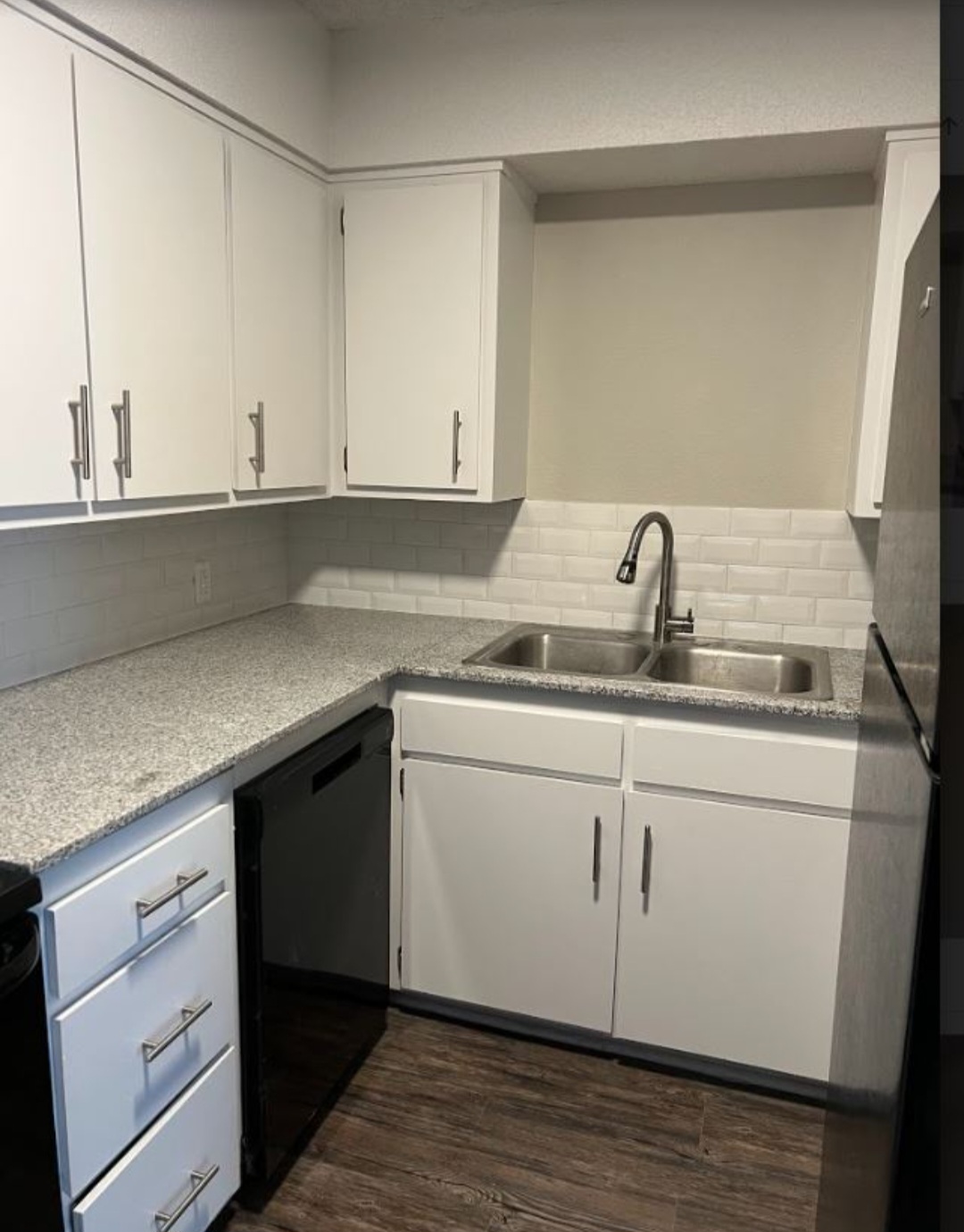 a kitchen with white cabinets and black appliances at The Courtyard