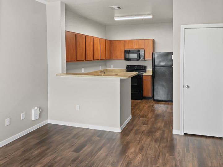 an empty kitchen with wood floors and a refrigerator at The West University Gardens
