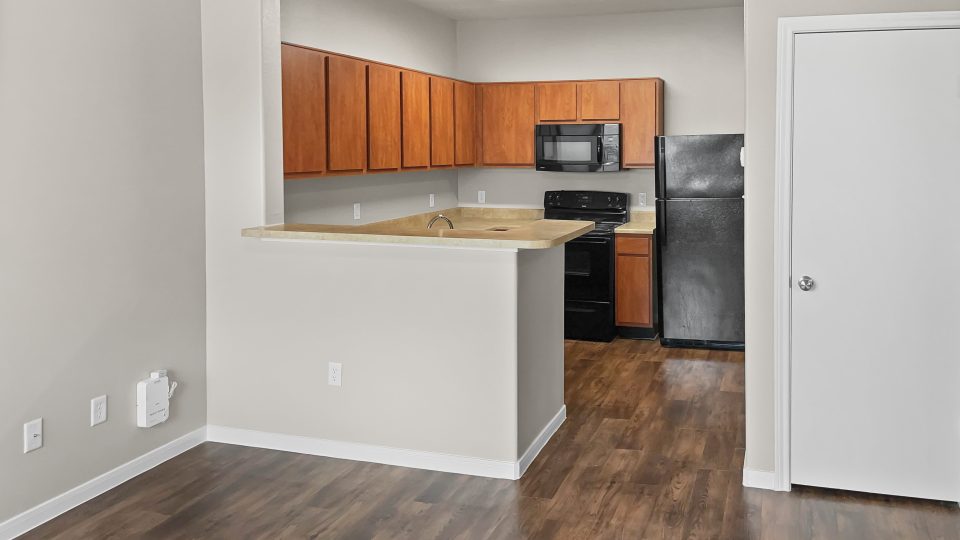 an empty kitchen with wood floors and a refrigerator at The West University Gardens