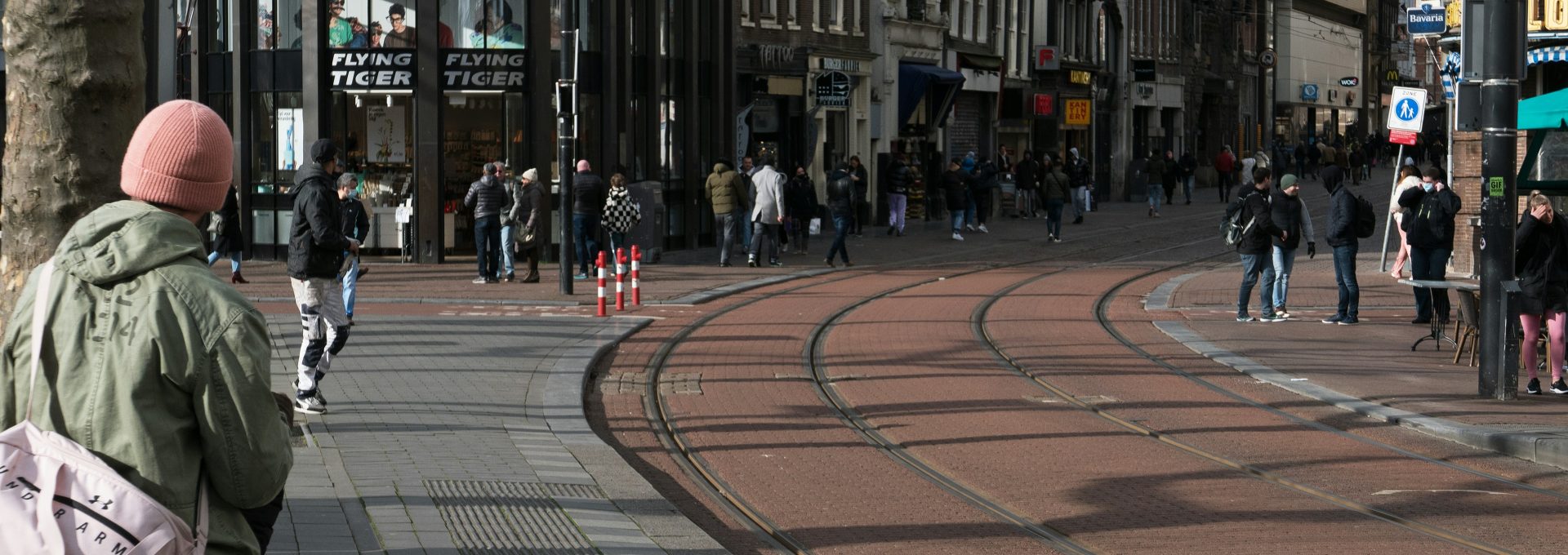 a group of people walking down a street next to tall buildings