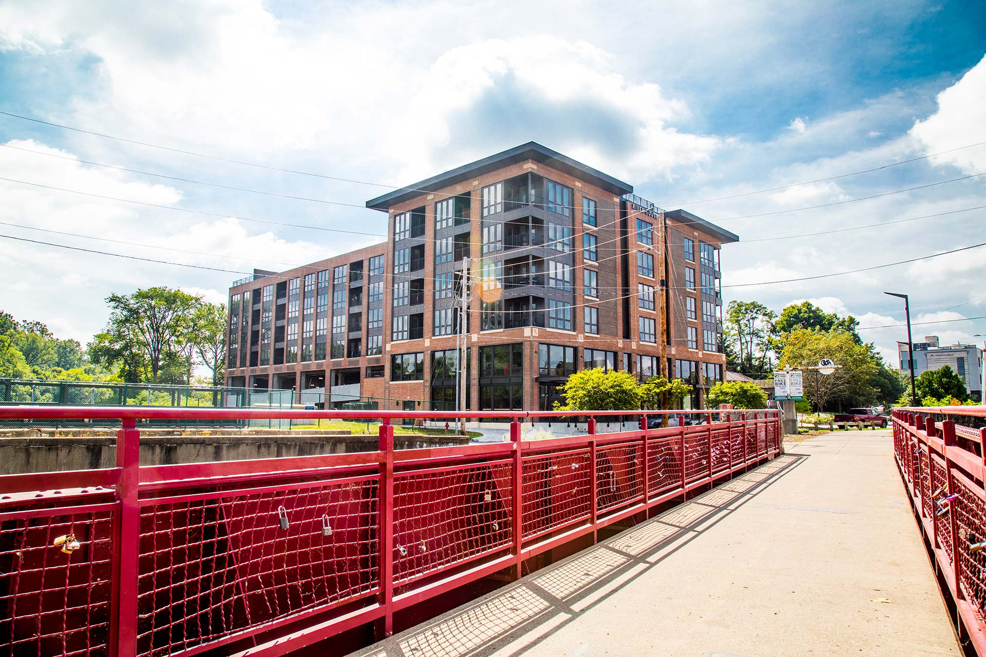 a red bridge over a river with a building on the other side at The River House