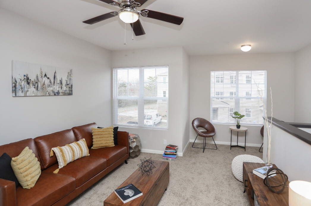 a living room with a couch, coffee table and ceiling fan at The Alpine Studios