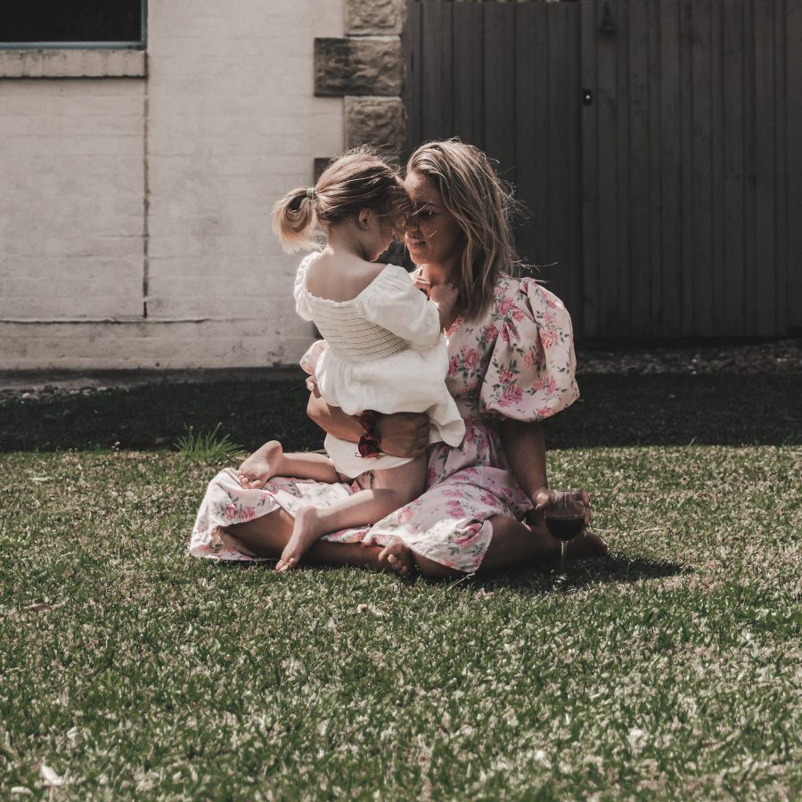 a woman and a little girl sitting on the grass at The parcHAUS at Firewheel Parkway