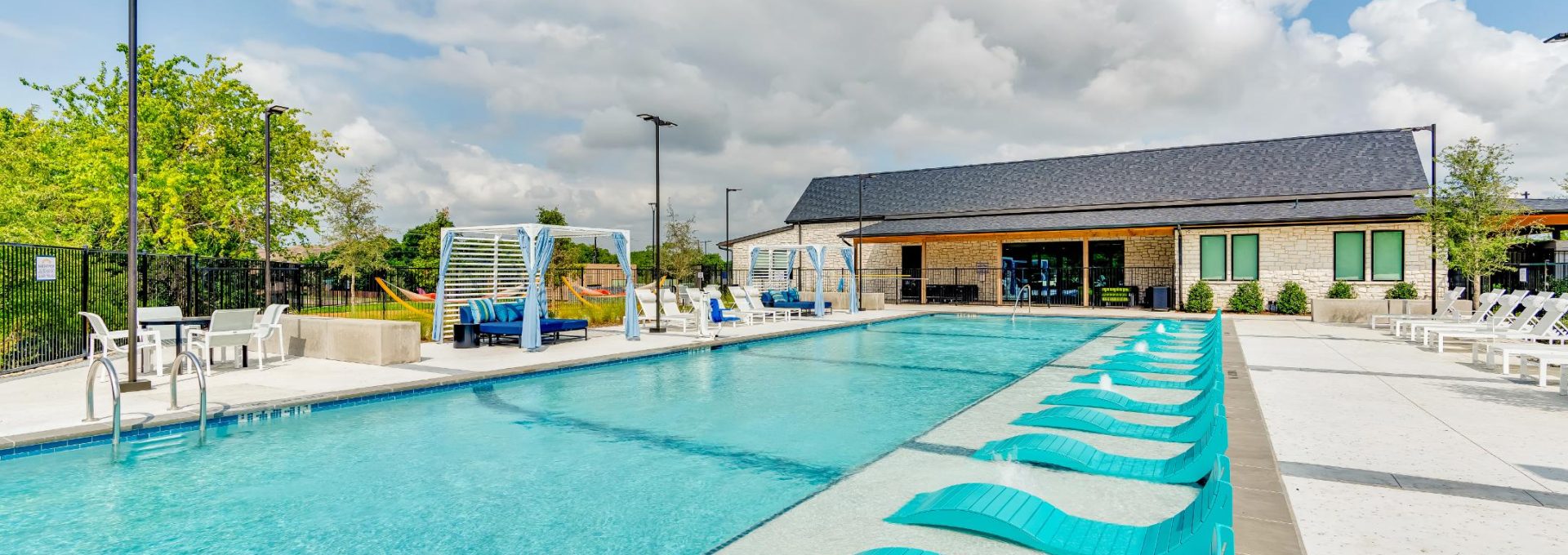a pool with blue lounge chairs and a sunshade at The parcHAUS at Firewheel Parkway