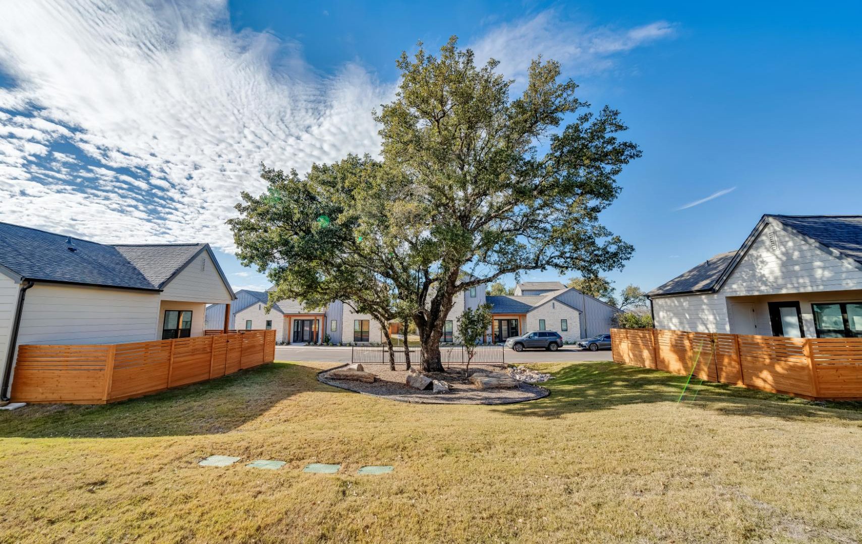 a yard with a fence and trees in the background at The parcHAUS at Mustang Drive
