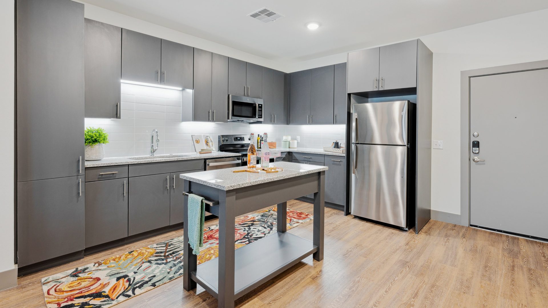 a kitchen with stainless steel appliances and wood floors at The BroadVue