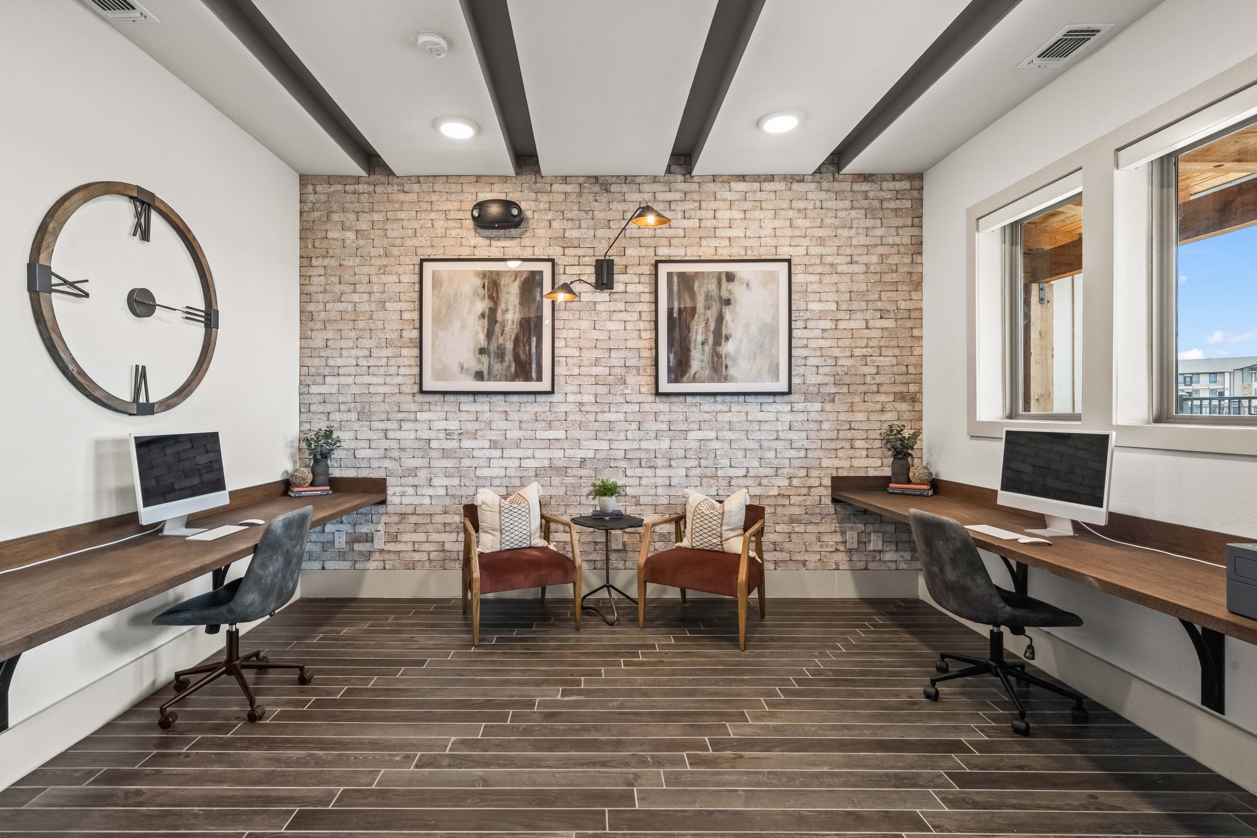 a modern office with a brick wall and wooden desk at The La Ventana at Canyon West Apartments