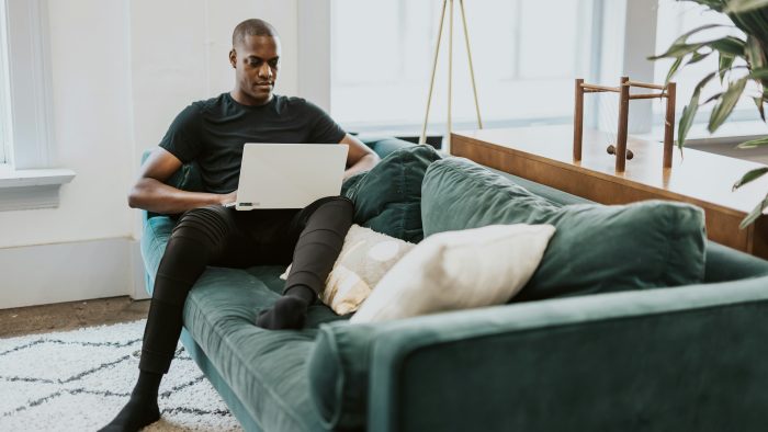 man in black crew neck t-shirt and blue denim jeans sitting on gray couch