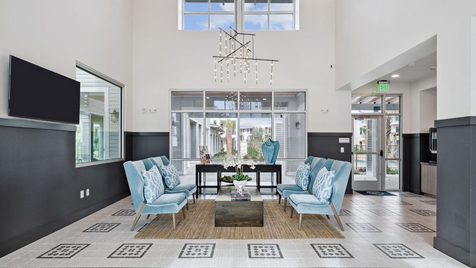 the lobby of a large apartment complex with blue chairs at The Legacy at Veramendi