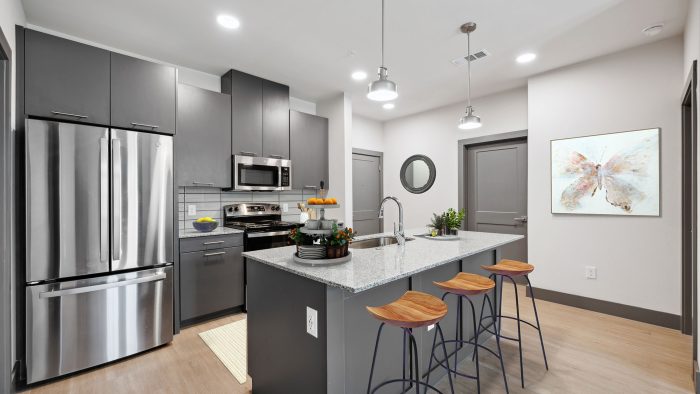 a kitchen with stainless steel appliances and gray cabinets at The Legacy at Veramendi