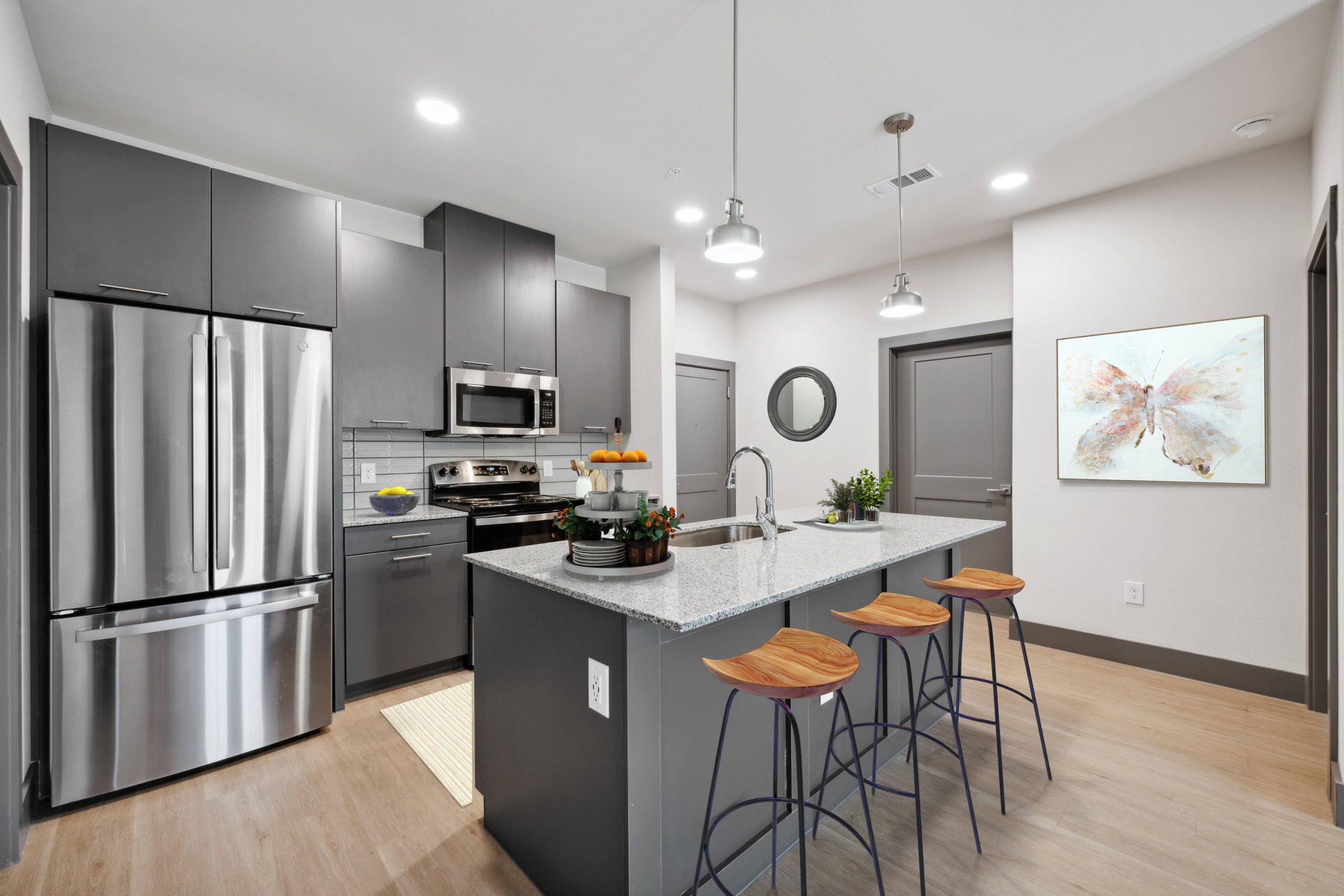 a modern kitchen with stainless steel appliances and gray cabinets at The Legacy at Veramendi