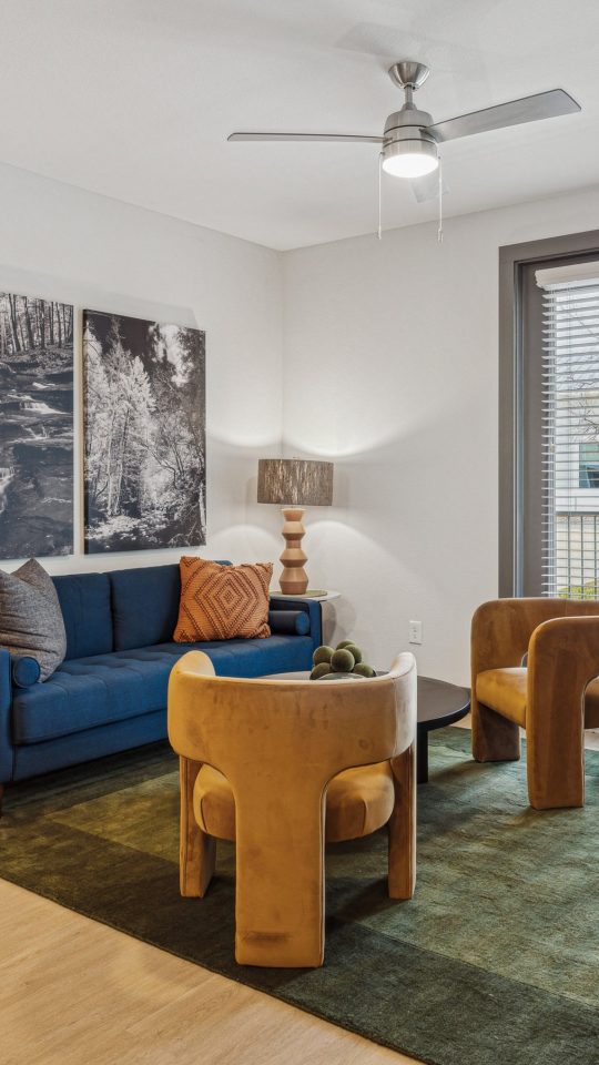 a living room with a blue couch and a large window at The Legacy at Veramendi