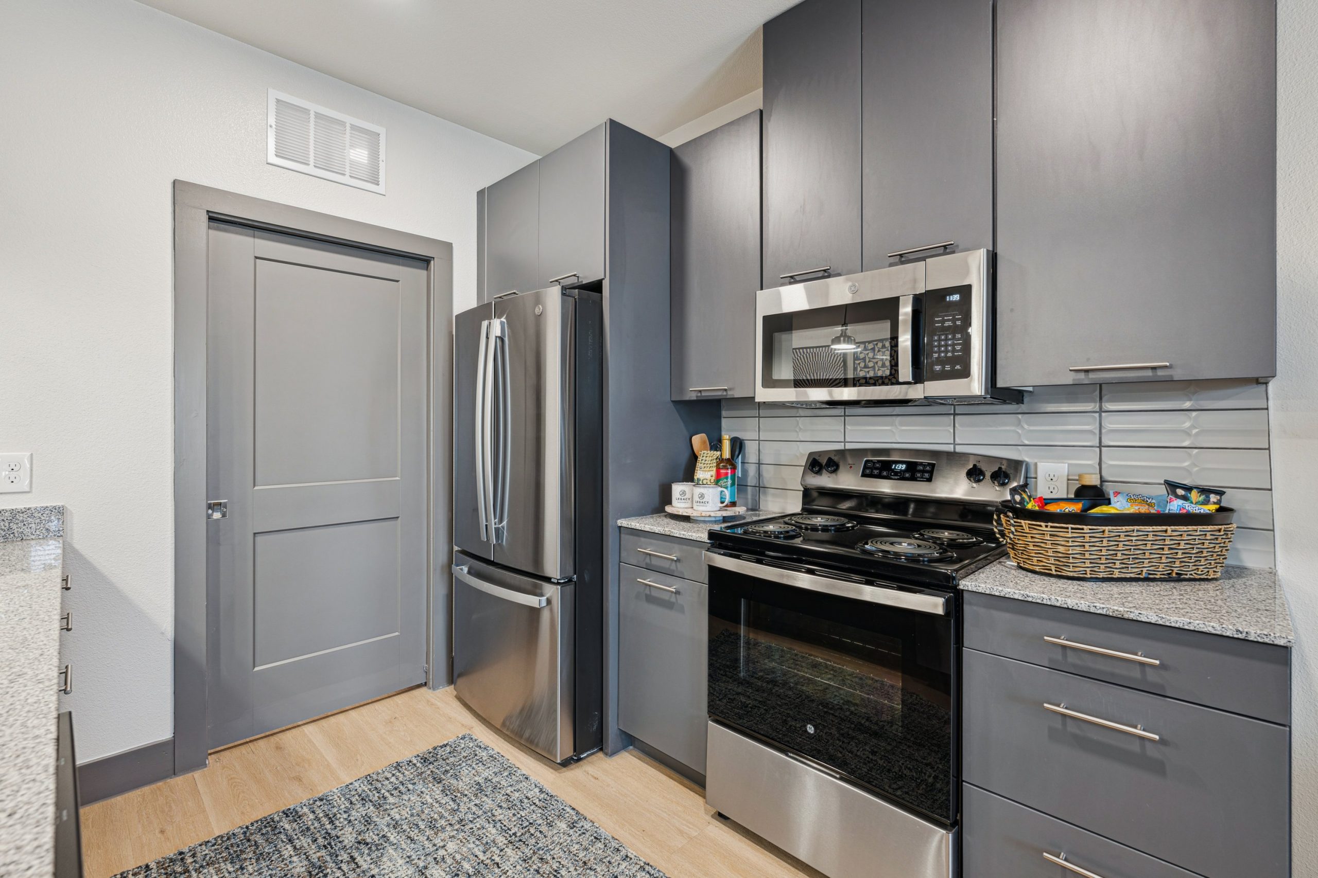 a kitchen with stainless steel appliances and gray cabinets at The Legacy at Veramendi