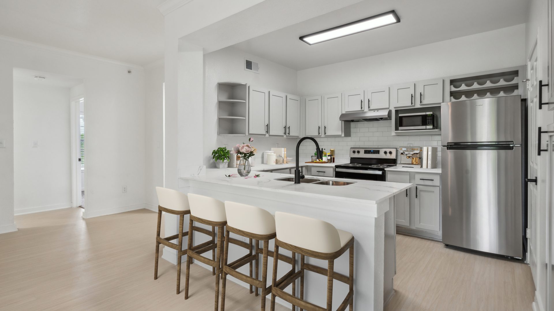 a white kitchen with stainless steel appliances and bar stools at The Stetson