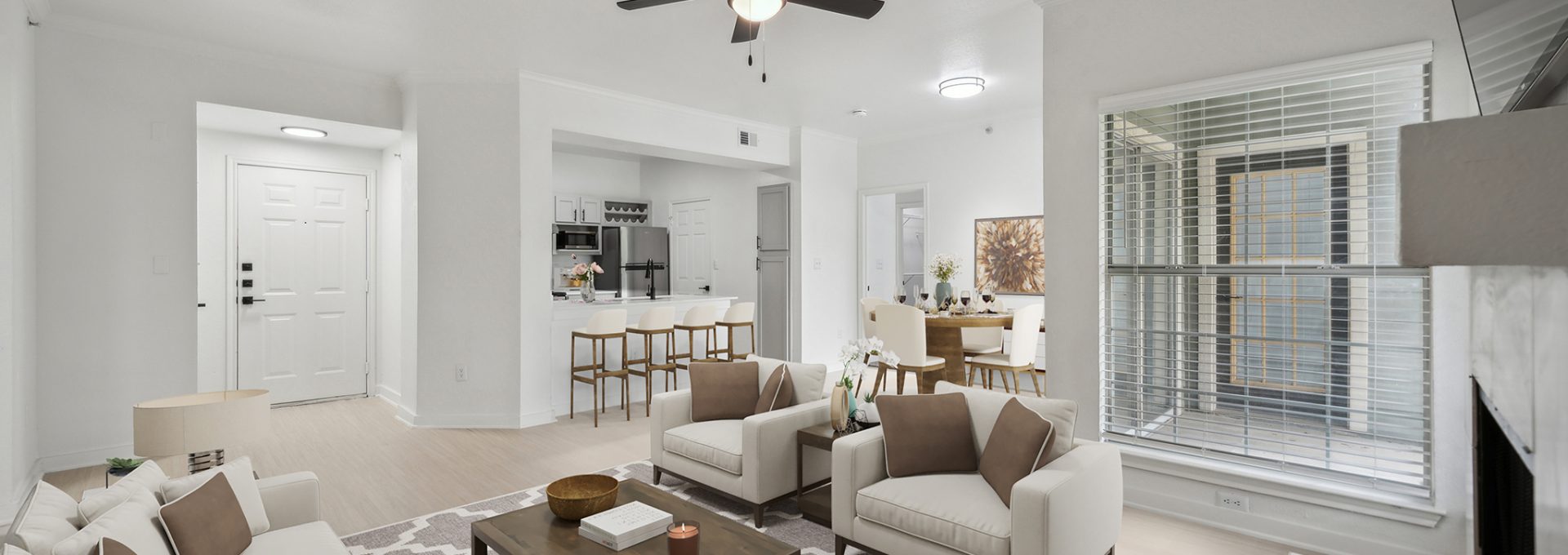 a living room with a ceiling fan and white walls at The Stetson