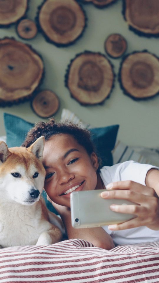 Woman and dog take a selfie in bed.