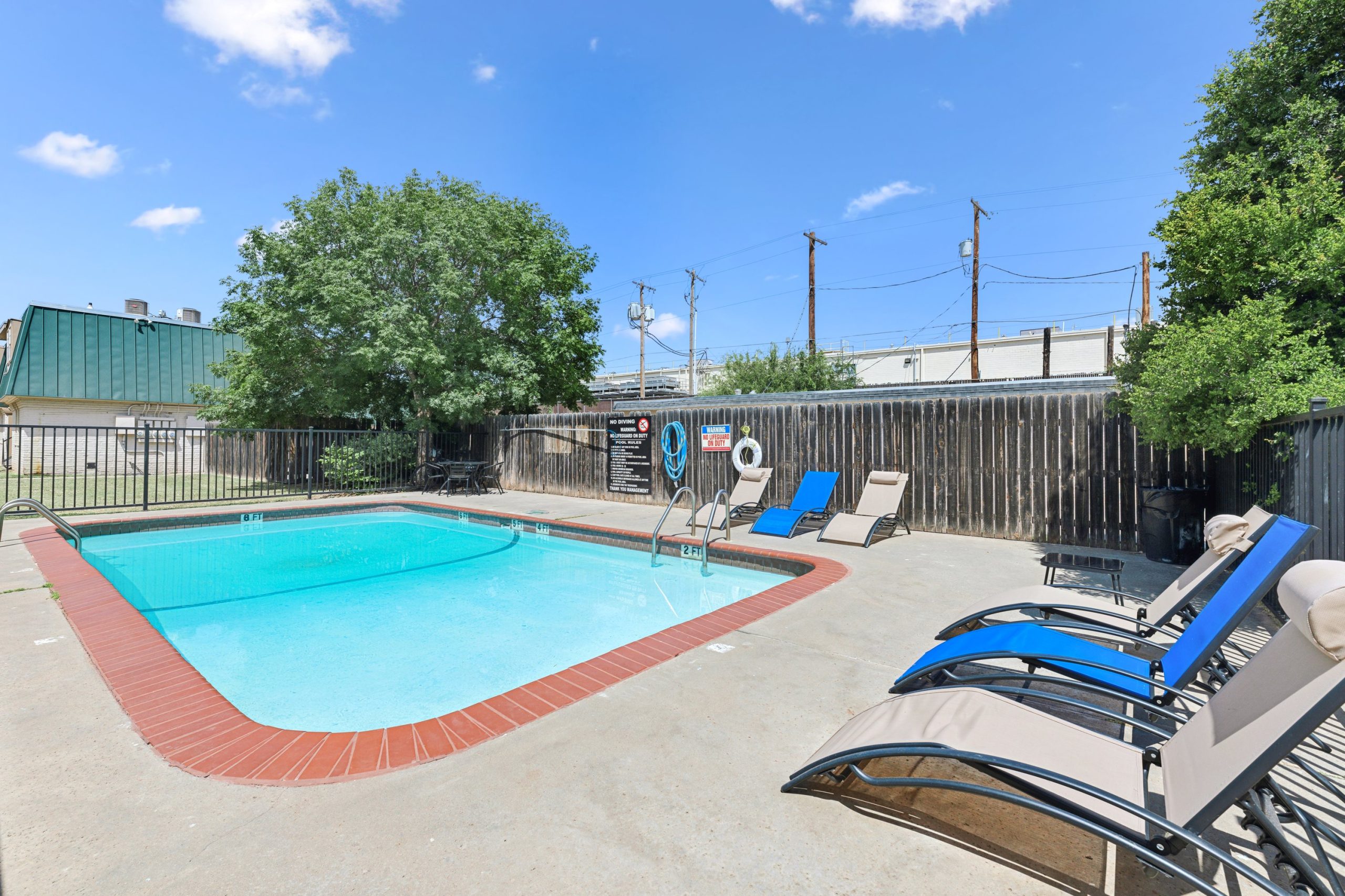 a pool with lounge chairs and a fence around it at The Crestwood Terrace