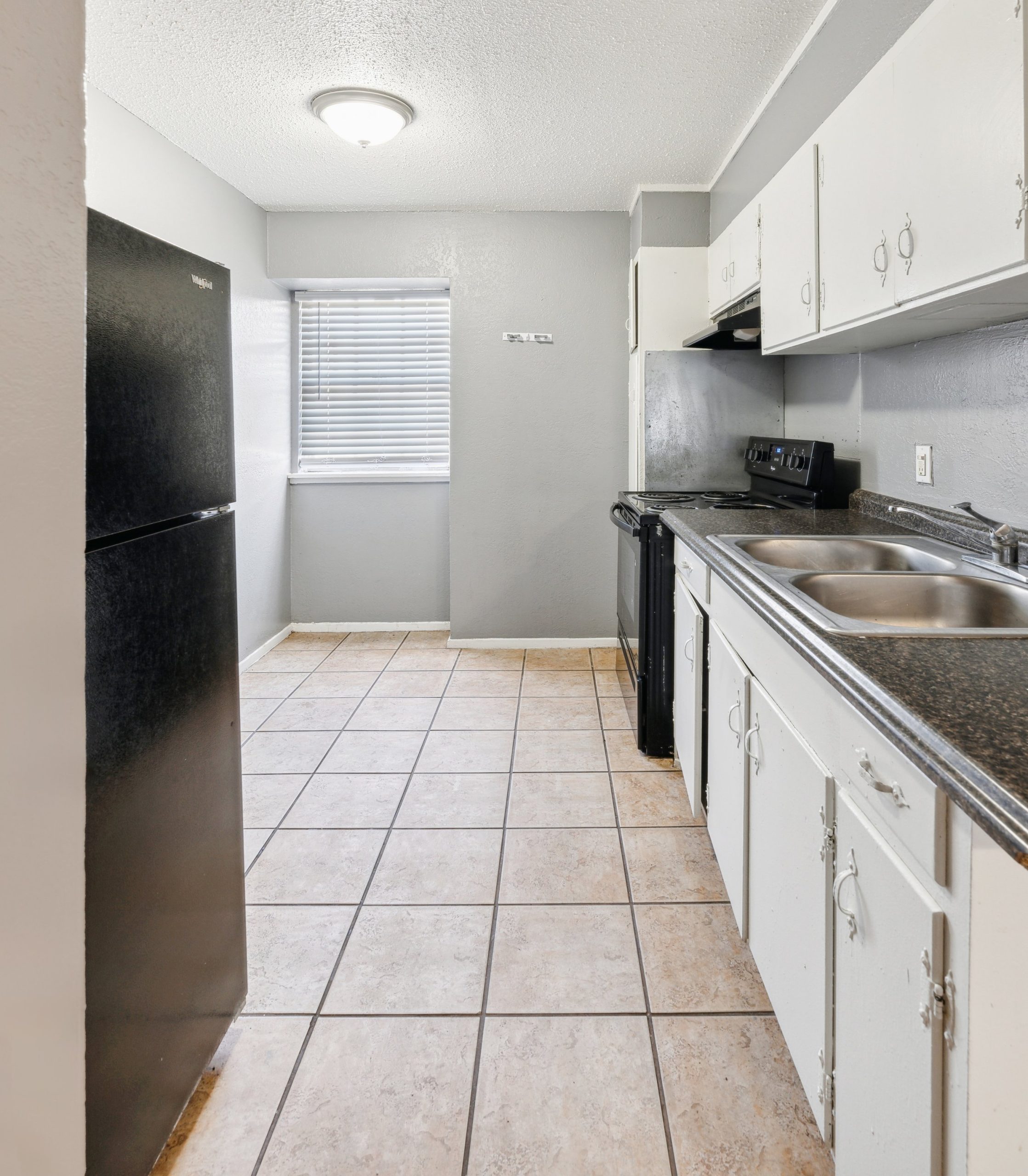 a kitchen with black appliances and white cabinets at The Crestwood Terrace