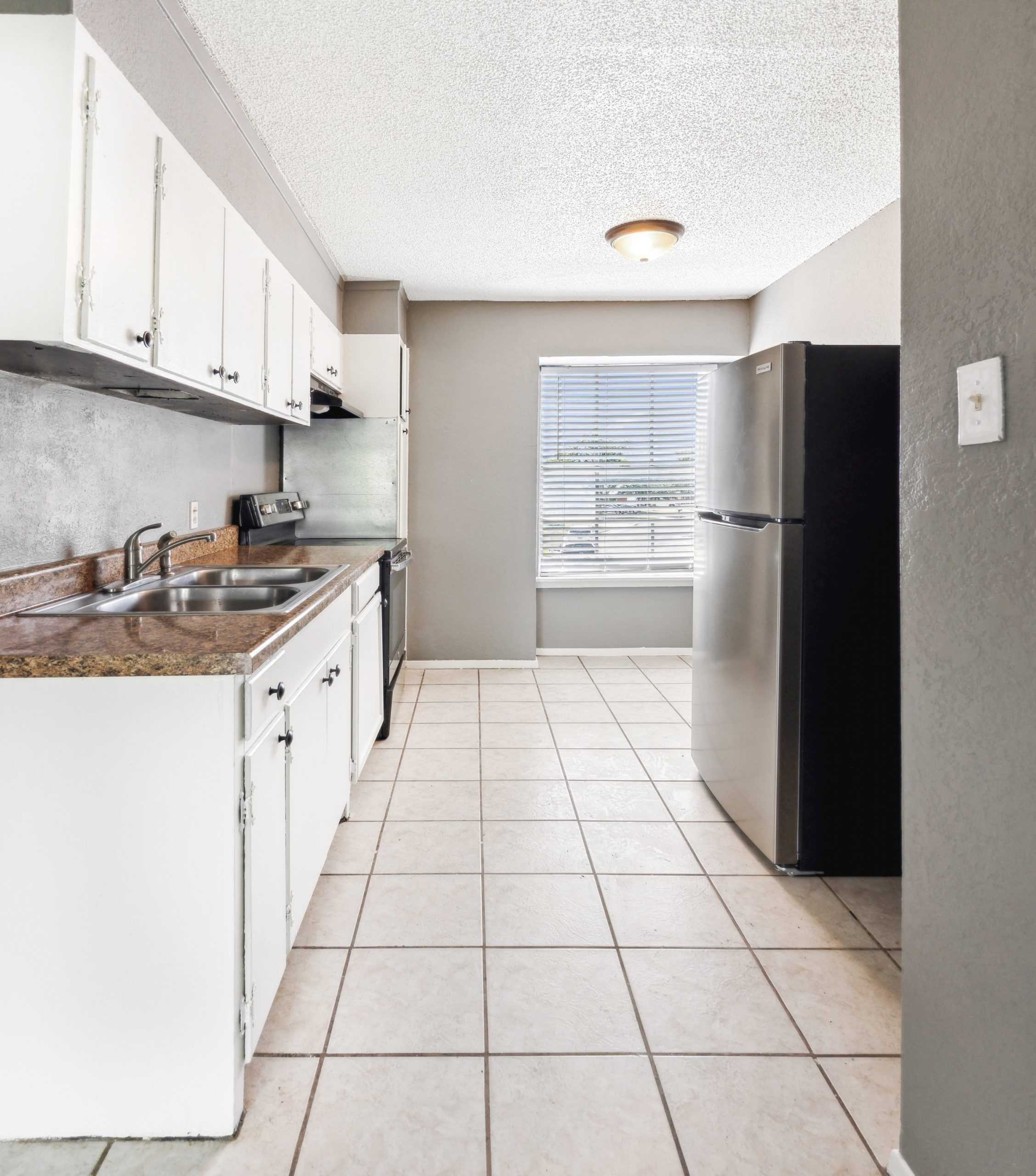 a kitchen with tile floors and stainless steel appliances at The Crestwood Terrace