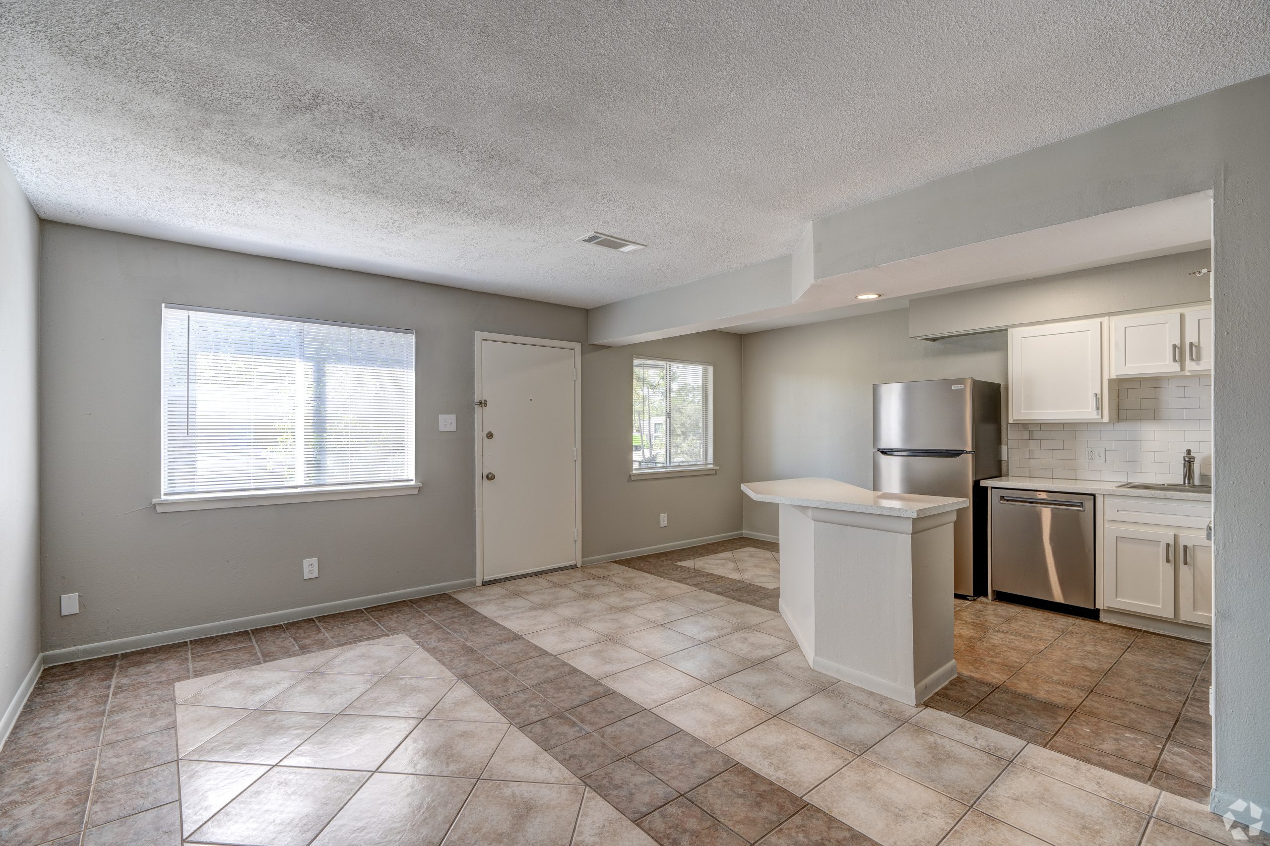 an empty kitchen with tile flooring and a refrigerator at The Westview Pines
