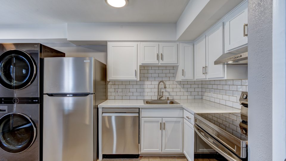 a kitchen with stainless steel appliances and a washer and dryer at The Westview Pines