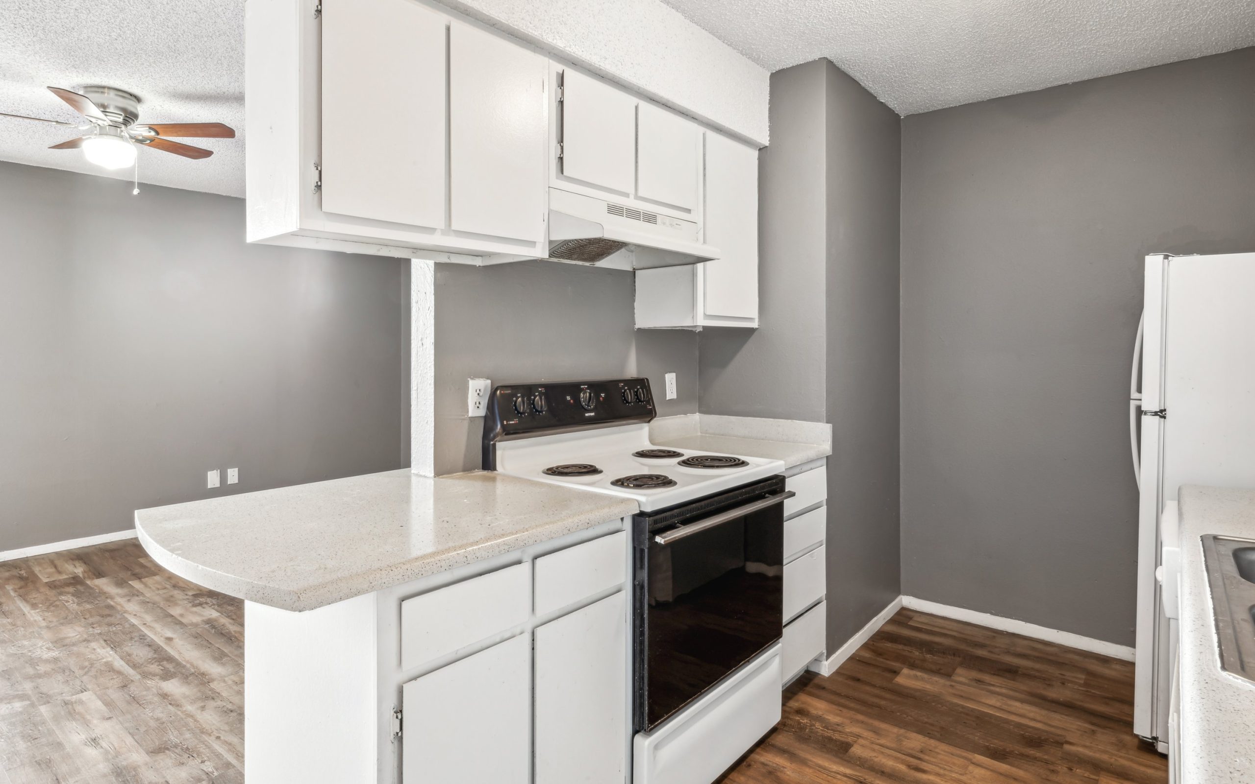 a kitchen with white cabinets and gray appliances at The Alamo Village Apartments