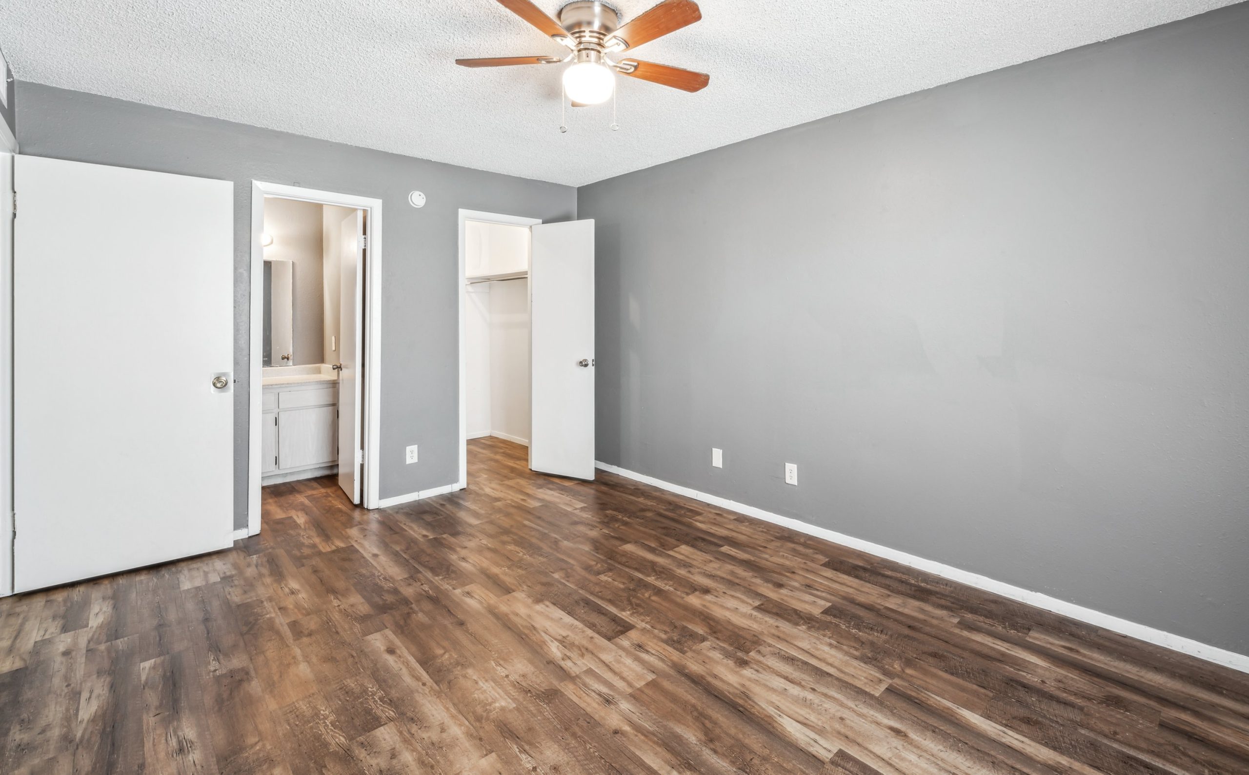 empty room with hardwood floors and ceiling fan at The Alamo Village Apartments