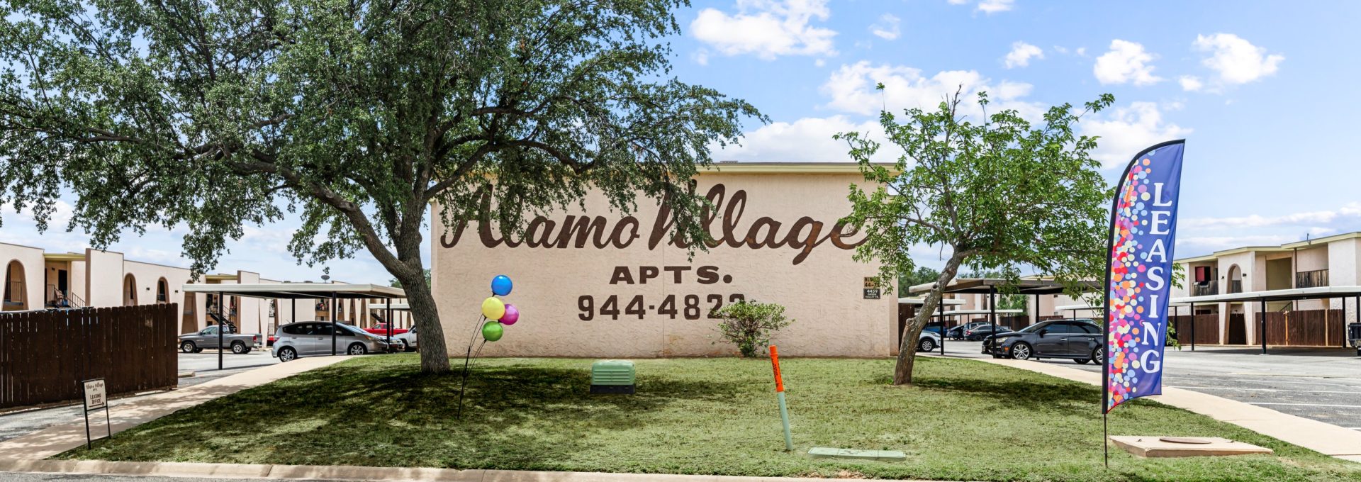 the sign for the village apartments in san antonio at The Alamo Village Apartments
