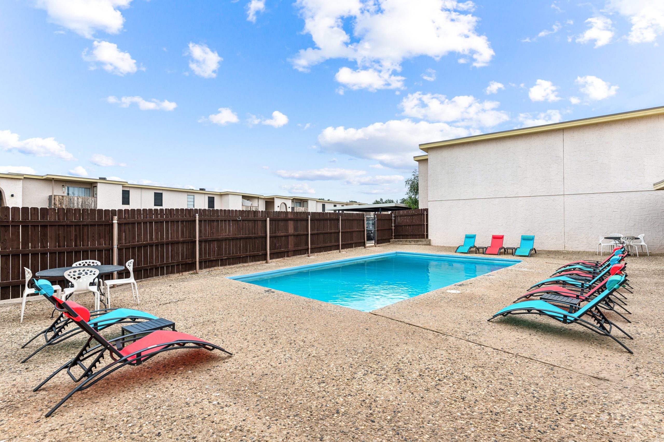 a pool with lounge chairs and a patio area at The Alamo Village Apartments