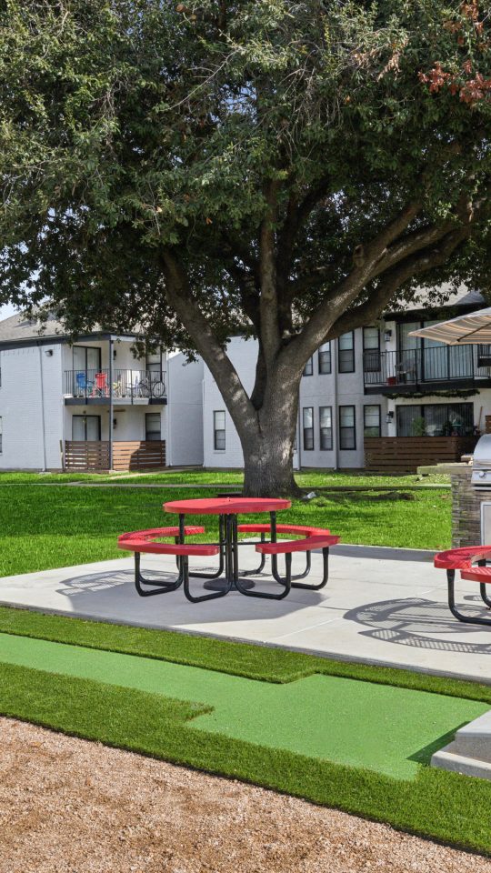 a picnic table and benches in front of a large apartment complex at The Brookbend